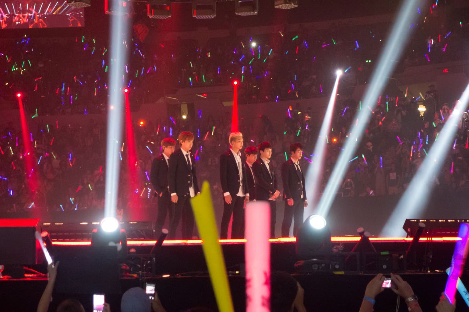 BTS en el escenario del KCON 2014 en Los Ángeles, con el público agitando barras de luz