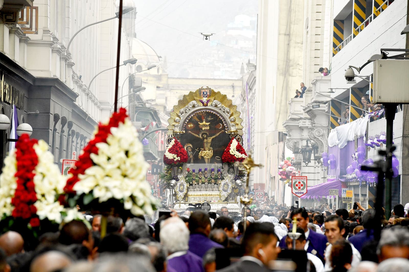 El anda del Señor de los Milagros avanza por una calle del Centro de Lima entre una multitud de fieles vestidos de morado