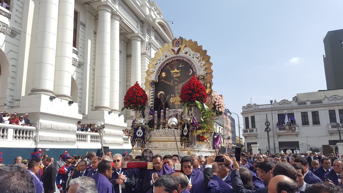 El anda del Señor de los Milagros frente al Congreso de la República, cargada por hermanos de la hermandad vestidos de morado